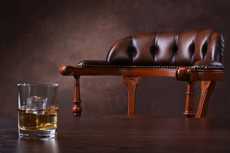 棕色背景木桌上的老式椅子和威士忌