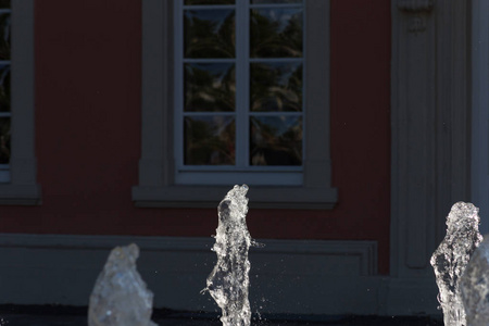在六月的一个阳光明媚的日子里，在德国南部，你看到一座历史建筑前的喷泉上有明亮的水珍珠。