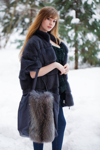 全长肖像年轻美丽优雅的黑发女子穿着毛皮外套。冬天，时髦的女孩在街上散步。