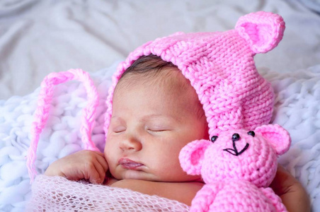 可爱可爱的可爱的新生婴儿女孩穿着粉红色有趣的帽子，耳朵睡觉。坚强安详的新生儿睡眠观念形象..