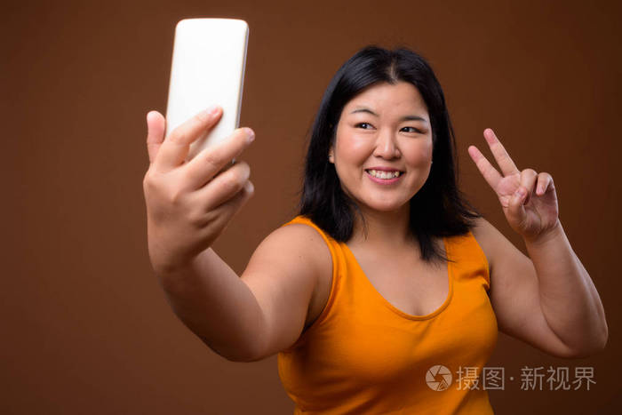 美丽的超重亚洲妇女使用手机采取自拍