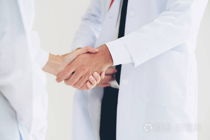 白色背景下的医生与另一位医生握手,展示专业医护人员的成功和团队