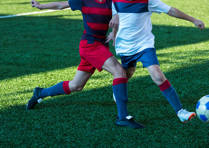 男孩篮球技巧足球队的男孩穿着红色蓝色白色运动服在绿色的球场上踢