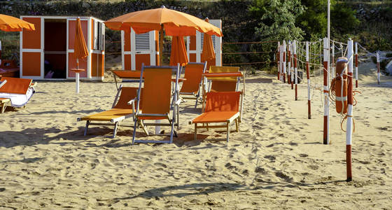 意大利维雅斯特海滩上的橙色雨伞和躺椅，目的地是亚得里亚海岸阿普利亚