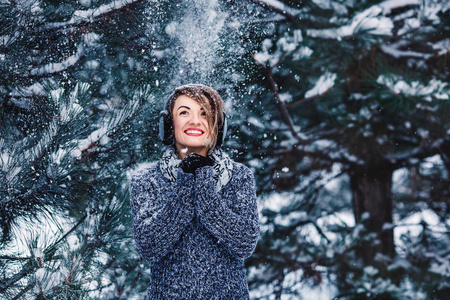 在冬季森林的毛衣时尚开朗的女孩。树上的雪落在女孩身上