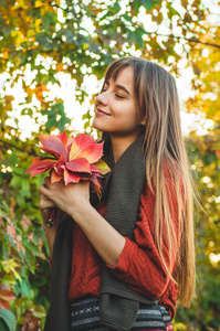 美丽浪漫的女孩户外享受自然持有叶子在手中。美丽的秋天模型与挥舞的辉光头发。太阳灯