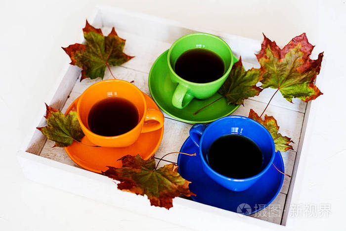 五颜六色的茶或咖啡放在白色背景上的木箱里，上面装饰着干燥的枫叶。 秋天的季节顶部景色。