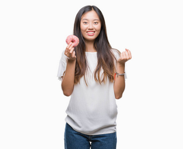 年轻的亚裔女性在孤立的背景下吃甜甜圈