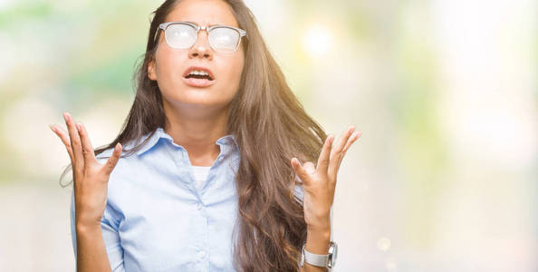 年轻漂亮的阿拉伯女人戴着眼镜，在孤立的背景上疯狂疯狂地大喊大叫，咄咄逼人的表情和手臂抬起。挫折的概念..