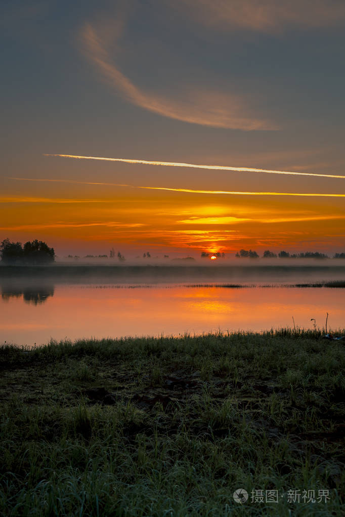 雾蒙蒙的早晨，河岸上的日出