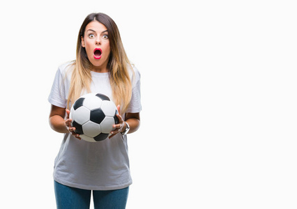 年轻的美女抱着足球在孤立的背景下惊恐的脸，恐惧和兴奋的表情