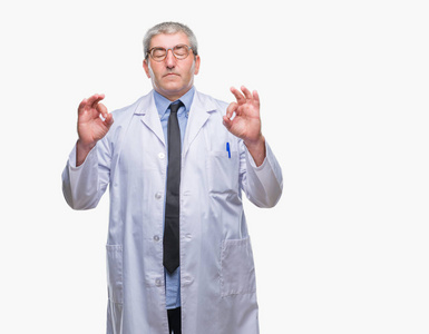 英俊的高级医生，科学家职业男子穿着白色外套在孤立的背景下放松和微笑，闭着眼睛做冥想手势用手指。瑜伽概念。