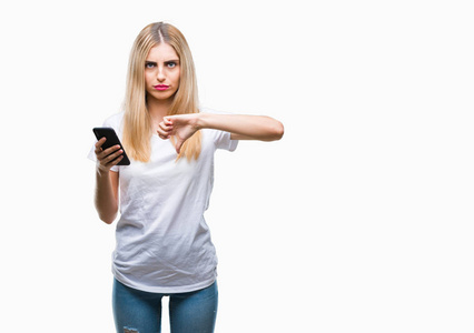 年轻漂亮的金发女性，在孤独的背景下使用智能手机，愤怒的脸，消极的迹象显示不喜欢用拇指向下，拒绝的概念