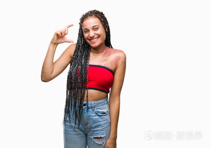 年轻的辫子非洲裔美国人，有色素沉着缺陷的出生标记，在孤立的背景上，微笑和自信的手势与手做大小标志与手指，同时看和相机。衡量概念。