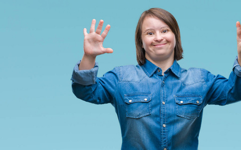 年轻的成年妇女患有唐氏综合症，在孤立的背景下，用手指数字9，同时微笑，自信和快乐。