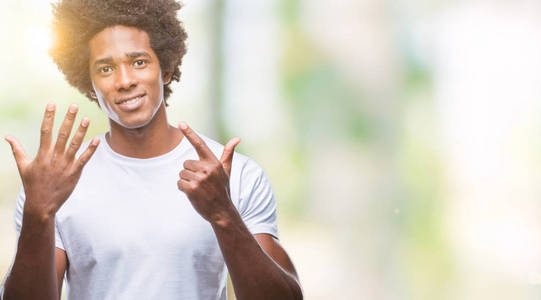 美国黑人男子在孤立的背景显示和指向7号手指，同时微笑自信和快乐。