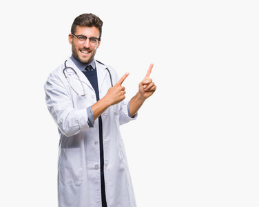 年轻英俊的医生男子在孤立的背景上微笑着，看着相机，用两只手和手指指向一边。