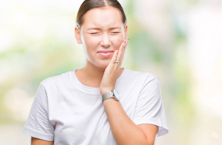 年轻美丽的白种人妇女，由于牙痛或牙齿上的牙齿疾病，在孤立的背景下用手触摸嘴，表情痛苦。牙医的概念。