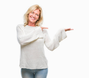 中年金发女子穿着冬季毛衣，在镜头前惊讶和微笑，同时用手和手指指点。