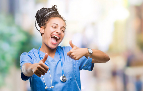 年轻的辫子非裔美国女孩专业外科医生在孤立的背景上批准做积极的手势，用手竖起大拇指，微笑和快乐的成功。 看着相机赢家的手势。