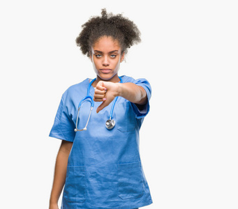 年轻的AFRO美国医生女人在孤立的背景上看起来不高兴和愤怒，表现出拒绝和消极的拇指向下的手势。 不好的表情。