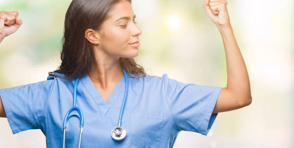 年轻的阿拉伯医生外科医生女士在孤立的背景上显示手臂肌肉微笑自豪。 健身理念。