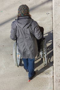 坐轮椅的老太太在德国南部的城市公园散步，2月，在一个历史城市的晴天