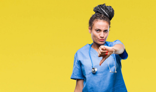 年轻的辫子非裔美国女孩专业外科医生在孤立的背景上看起来不高兴和愤怒，表现出拒绝和消极的拇指向下的手势。 不好的表情。