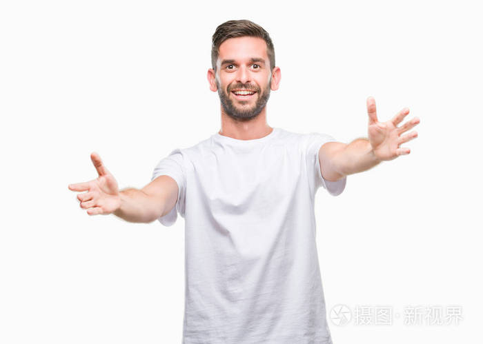 年轻的英俊男子在孤立的背景下,看着相机,张开双臂拥抱微笑.