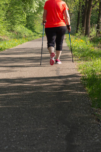 诺德女士在春天的公园里散步，红色的夹克和明亮的阳光照耀着幸福的锻炼