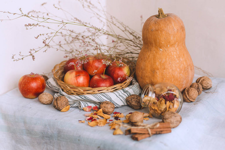 用绳子包裹的肉桂棒, 柳条篮子里的苹果, 站在条纹亚麻布核桃和花瓣上, 这仍然是一种生活。秋冬舒适的家的概念