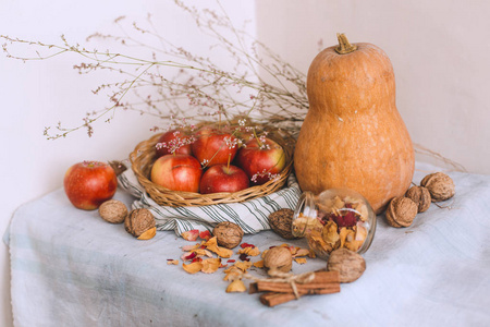 用绳子包裹的肉桂棒, 柳条篮子里的苹果, 站在条纹亚麻布核桃和花瓣上, 这仍然是一种生活。秋冬舒适的家的概念