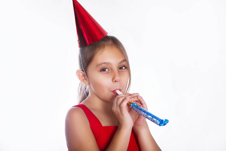 带着生日帽和白色背景哨子的微笑小女孩。 庆祝和聚会