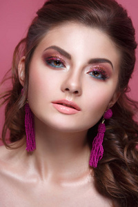 时尚美容肖像一个美丽的女孩与一个明亮的化妆和一个优雅的发型在粉红色的背景。
