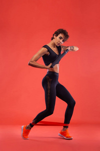 一个强壮的运动女性跑步者穿着紧身的健身服在黑色的场地上。