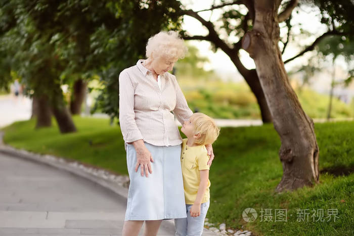 美丽的奶奶和她的小孙子一起在公园散步.奶奶和孙子