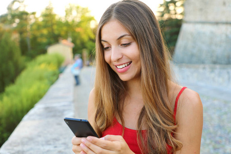 幸福美丽的女人用手机在户外发送信息