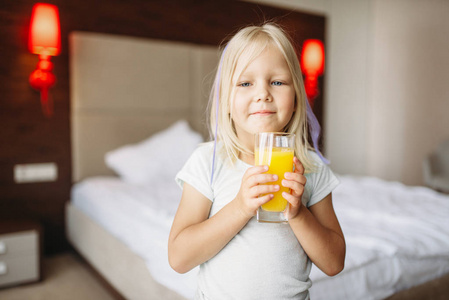 家里卧室里有一杯新鲜橙汁的小女孩。 真正无忧无虑的童年快乐时光