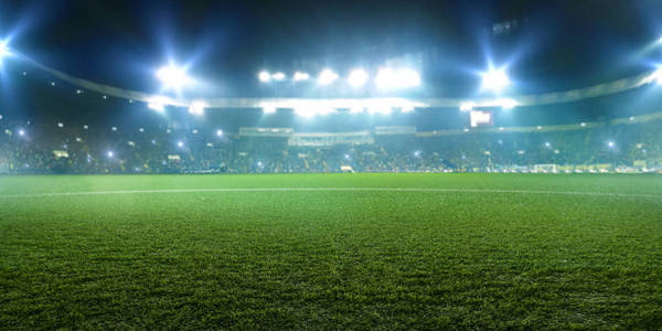 足球场闪亮的灯光从田野的草地上看到。 没有人在操场上为后台的游戏迷主持法庭