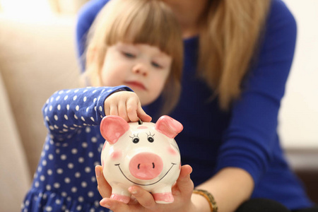 孩子小女孩胳膊投入硬币入 piggybank