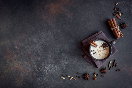 传统印度马萨拉柴茶在陶瓷杯与配料。 肉桂豆蔻八角辣红茶与牛奶在黑暗的背景复制空间。