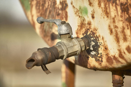 一个旧的生锈的水龙头的细节，一个蓄水池，用于装载农用车辆的燃料。