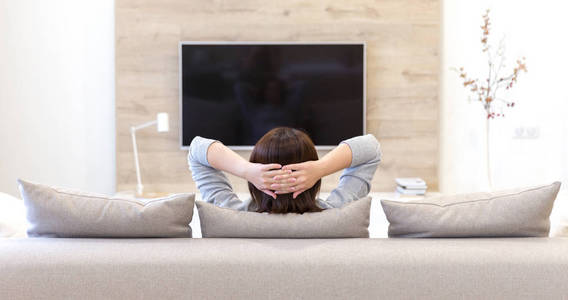 年轻的女人在房间里看电视照片