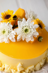 芒果芝士蛋糕，黄色果冻，配上鲜花和新鲜芒果片，白色背景垂直组成