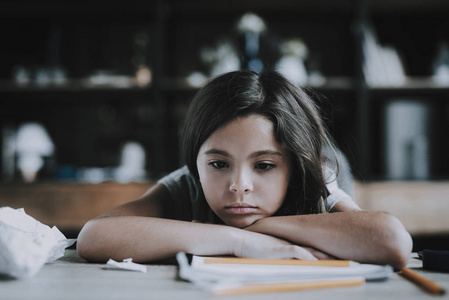 孩子懒惰躺在桌子上的小女孩表现出无聊的表情.