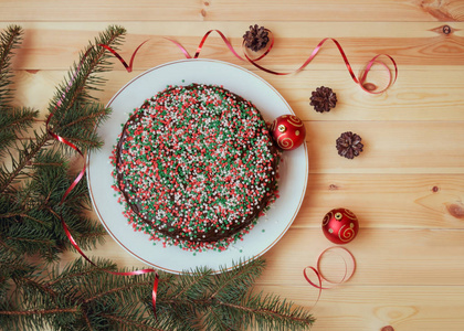 圣诞蛋糕装饰着红白和绿色的糖星，树枝和圣诞装饰品。 平躺顶部视图。