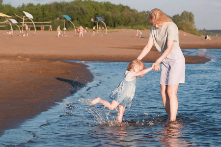 妈妈和女孩在海滩上玩日落和游泳