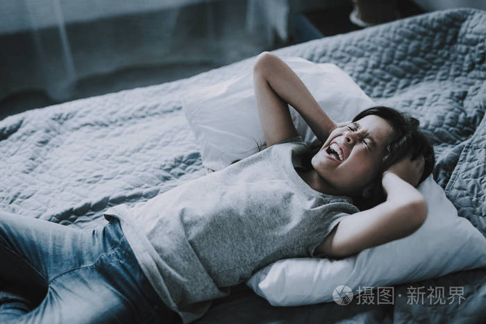 皱眉的小女孩在卧室里捂住耳朵.