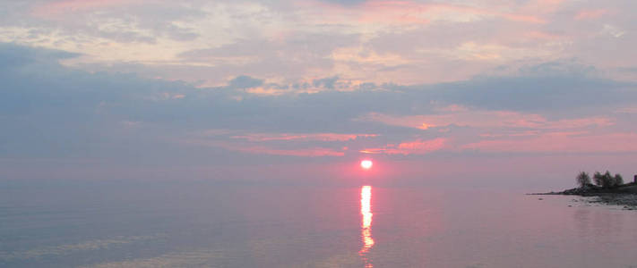 日落时海湾。 海上五彩缤纷的日出景观。 清晨的微妙颜色，蓝色和粉红色。 黎明前黄昏湖上的黎明寂静。