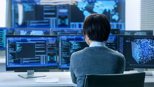 在系统控制室，技术操作员在他的工作站工作，多个显示器显示图形。 它的技术人员从事人工智能大数据挖掘神经网络项目。